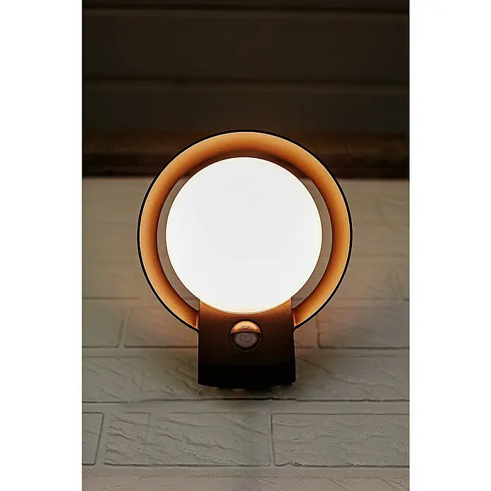 Lutec Polo LED-Sensor-Außenwandleuchte - 16,1 W, L x B x H: 18 x 16,4 x 16,2 cm, Anthrazit, Warmweiß - Diese Aufnahme zeigt eine runde, strahlende Wandleuchte mit Bewegungssensor an einer hellen Ziegelwand. Das Licht sorgt für eine angenehme Atmosphäre.