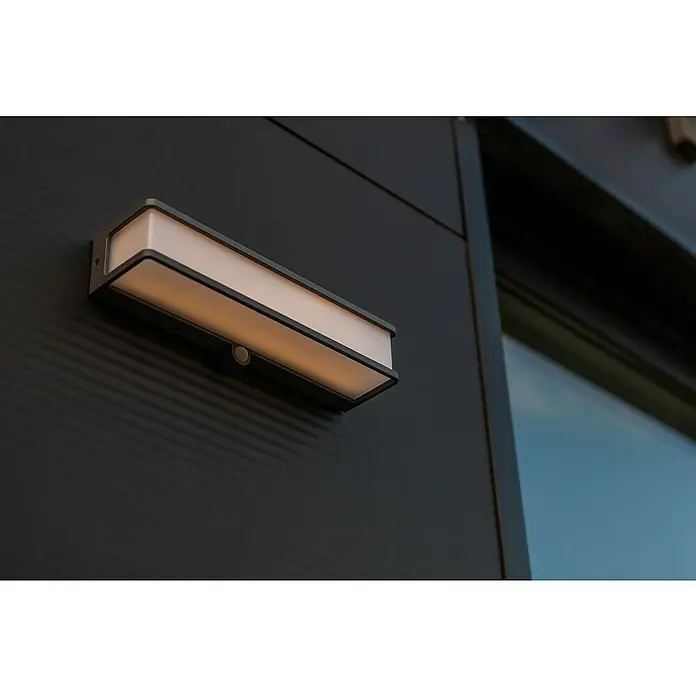 Lutec Doblo Solar-Außenwandleuchte - 16,5 W, L x B x H: 35 x 9,1 x 9 cm, Anthrazit, IP54, 1.800 lm - Moderne Wandleuchte mit Bewegungsmelder an einer schwarzen Fassade. Das Lichtdesign ist schlicht und elegant.