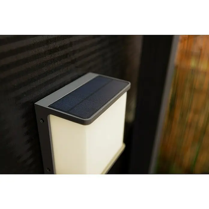 Lutec Doblo Solar-Außenwandleuchte - 12 W, L x B x H: 15 x 8,9 x 17 cm, Anthrazit, IP44, 1.000 lm - Nahaufnahme einer stilvollen Solarleuchte an einer dunklen Wand, die modernes Design und umweltfreundliche Technologie vereint.