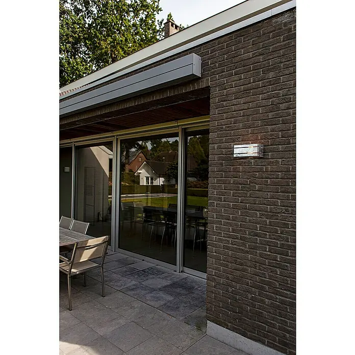 Lutec Außenwandleuchte Vidar - 40 W, 25 x 11,3 x 11 cm, Verzinkt, IP54 - Moderne Außenansicht eines Hauses mit einer eleganten Terrassenbeleuchtung und dunklen Ziegelsteinen, die eine stilvolle Atmosphäre schafft.