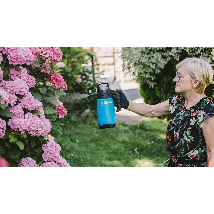 Matabi Sulfatadora Evolution 2 - Plástico - Primer plano de una mujer rociando hortensias rosas con un pulverizador Matabi azul para cuidar su jardín.