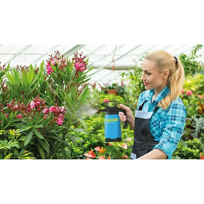 Matabi Sulfatadora Evolution 2 - Plástico - Una mujer rocía flores con un pulverizador azul para plantas Matabi Evolution 2 en un invernadero, rodeada de exuberante vegetación.