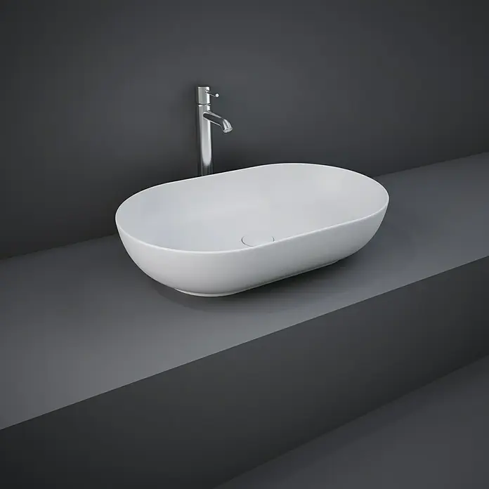 RAK Ceramics Feeling Aufsatzwaschbecken - 55 x 35 cm, Ohne Spezialglasur, Hahnloch: Ohne, Ohne Überlauf, Weiß, Matt - Elegantes Aufsatzwaschbecken aus weißer Keramik mit schlankem Chromhahn auf einer grauen Waschtischplatte.