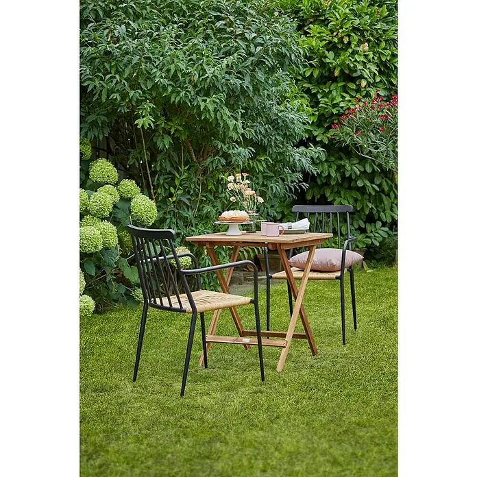Sunfun Balkontisch - L x B x H: 65 x 65 x 74 cm, Akazie, Klappbar, Quadratisch, Natur - Gartenszene mit einem Holztisch und zwei Stühlen. Der Tisch ist mit einem Kuchen und Blumen dekoriert und lädt zum Verweilen ein.