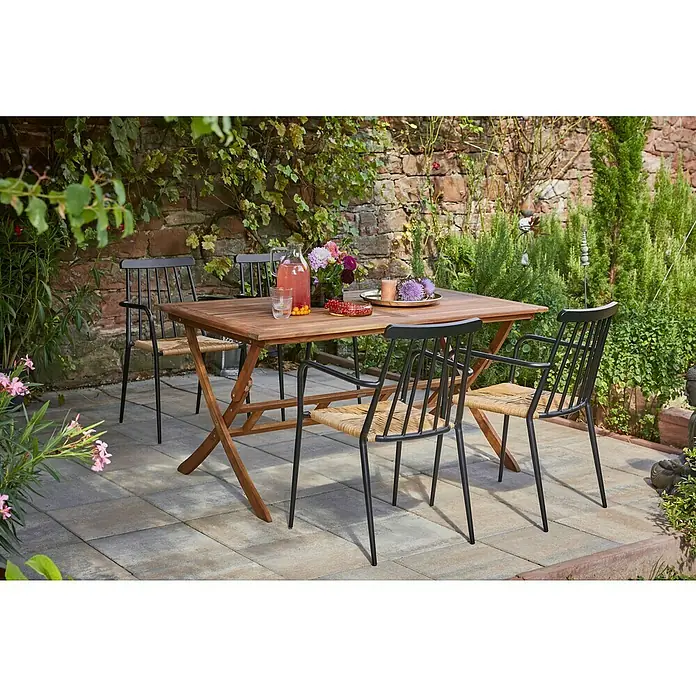 Sunfun Diana Gartentisch - L x B x H: 150 x 86 x 75 cm, Akazie, Rechteckig, Naturbraun - Outdoor-Szene mit einem quadratischen Holztisch und vier Stühlen mit schwarzem Gestell und naturfarbener Sitzfläche, umgeben von üppigem Grün.