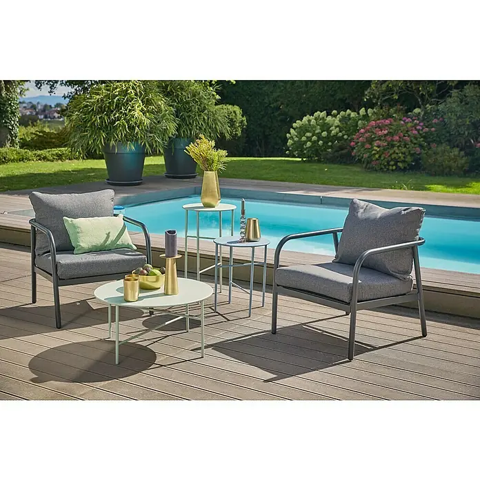 Loungesessel Olga - B x T x H: 67 x 76 x 63 cm, Schwarz/Grau - Gartenmöbel-Set mit zwei grauen Sesseln, runden Tischen, Pool und Pflanzen im Hintergrund. Perfekt zum Entspannen im Freien.