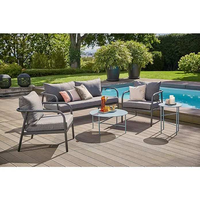 Loungesessel Olga - B x T x H: 67 x 76 x 63 cm, Schwarz/Grau - Gartenmöbel-Set mit grauem Sofa, Sesseln und runden Tischen auf einer Holzterrasse neben einem Pool, umgeben von üppigem Grün.