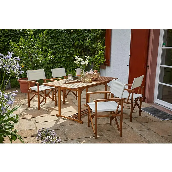 Sunfun Diana Gartentisch - L x B x H: 120 x 80 x 74 cm, Akazie, Rechteckig, Naturbraun - Ein Gartentisch mit vier Regiestühlen auf einer Terrasse mit Pflanzen. Das Set ist ideal für Mahlzeiten im Freien.