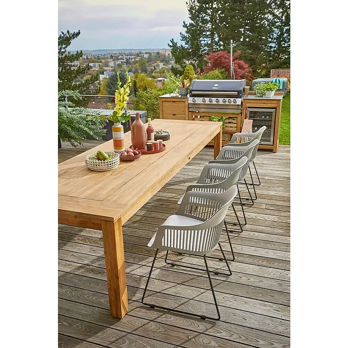 Sunfun Zoe Outdoorküchen-Modul Multifunktionsregal - Braun, B x T x H: 67,5 x 63 x 92 cm, Teakholz - Ein einladender Außenbereich mit einem Holztisch, umgeben von eleganten grauen Stühlen, perfekt für Mahlzeiten im Freien.
