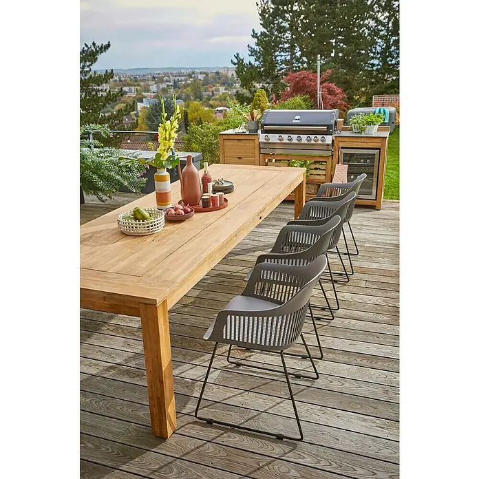 Sunfun Zoe Módulo de cocina exterior Armario con cajones - Marrón, An x Pr x Al: 58 x 63 x 92 cm, Madera de teca - Acogedor espacio al aire libre con una mesa de comedor de madera y sillas modernas, ideal para comidas al aire libre. La parrilla al fondo mejora el ambiente.