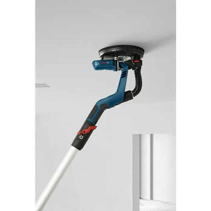 Bosch Professional Lijadora de pared y techo GTR55-225 - 550 W, Diámetro disco de lija: 225 mm - Una imagen de una lijadora de paneles de yeso con pértiga telescópica azul y negra unida a un techo blanco.