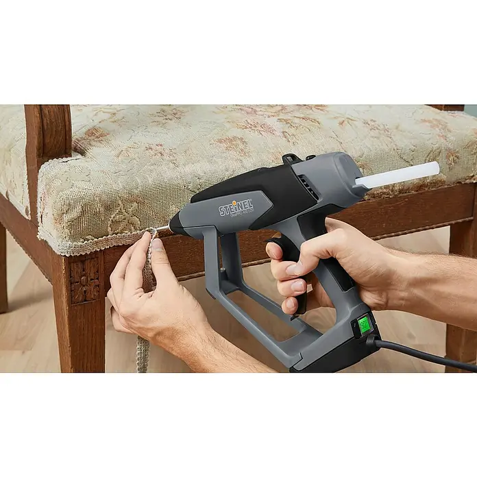 Steinel Klebepatronen Universal - 20 Stk., Transparent, Durchmesser Klebepatrone: 11 mm - Nahaufnahme einer Steinel GluPRO 400 LCD Heißklebepistole beim Anbringen einer Zierleiste an einem Stuhl.