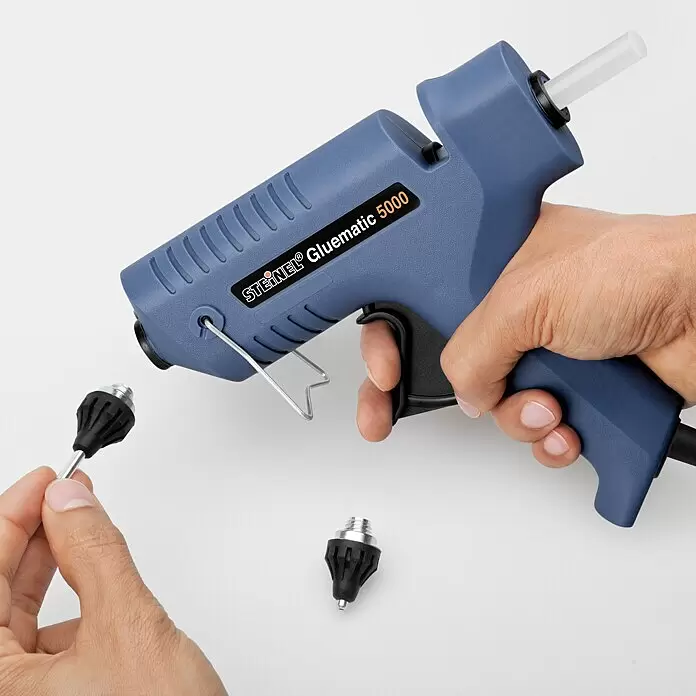 Steinel Heißklebepistole Gluematic 5000 - Durchmesser Klebepatrone: 11 mm, 500 W - Blaue STEINEL Gluematic 5000 Heißklebepistole mit weißem Klebestick, von Händen gehalten, mit austauschbaren Düsen.