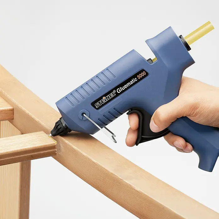 Steinel Heißklebepistole Gluematic 5000 - Durchmesser Klebepatrone: 11 mm, 500 W - Nahaufnahme einer Steinel Gluematic 5000 Heißklebepistole in Aktion. Präzises Kleben von Holzverbindungen mit dem Werkzeug.