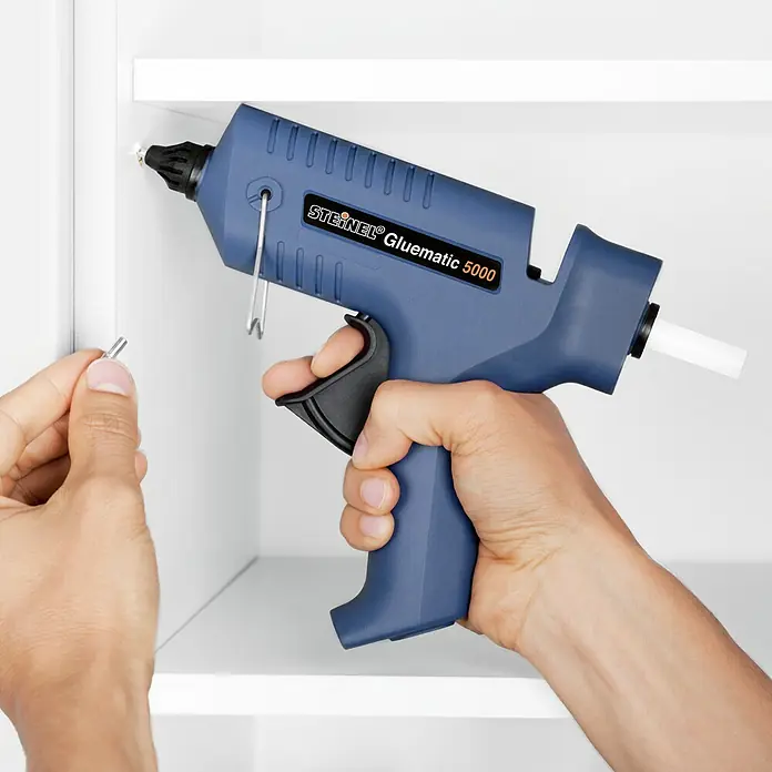 Steinel Heißklebepistole Gluematic 5000 - Durchmesser Klebepatrone: 11 mm, 500 W - Nahaufnahme einer Steinel Gluematic 5000 Heißklebepistole in Aktion, gehalten in einer Hand.