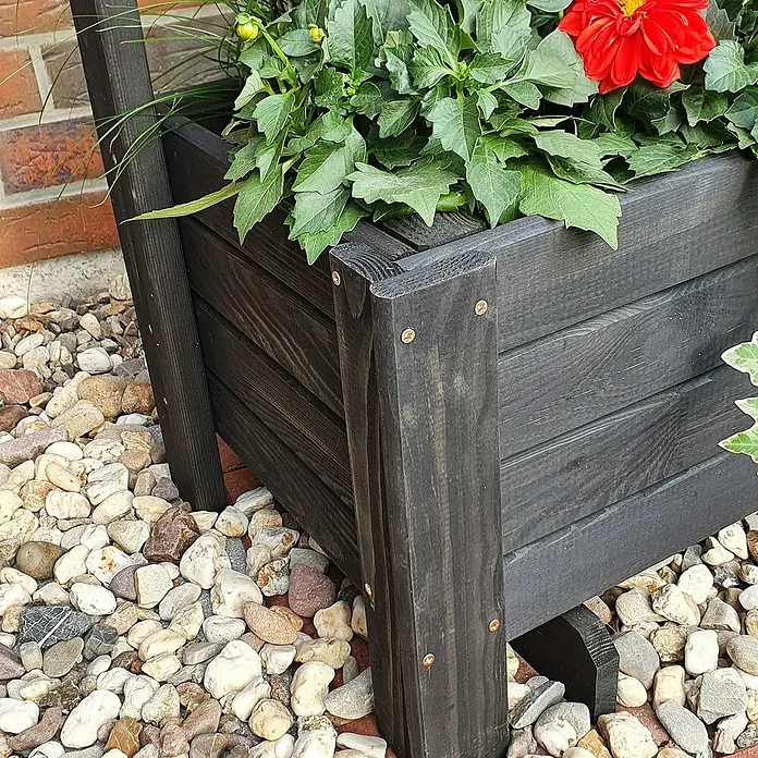 Promadino Pflanzkasten Romantica - Außenmaß (L x B x H): 80 x 38 x 140 cm, Holz, Anthrazit - Nahaufnahme eines schwarzen Blumenkastens aus Holz mit bunten Blumen, umgeben von dekorativen Kieselsteinen im Garten.