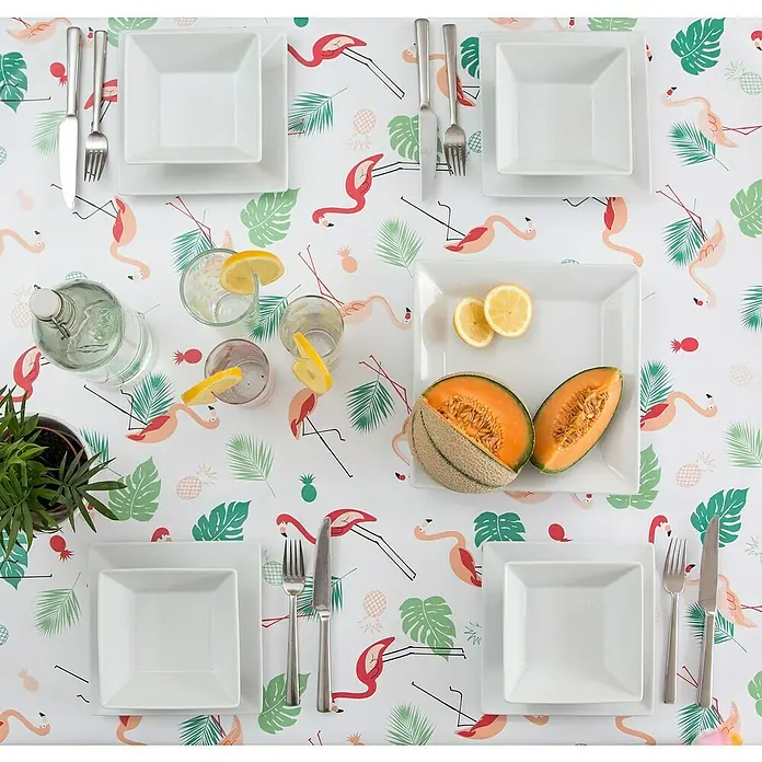 D-c-fix Manhattan Tischdecke Meterware Südsee - Mehrfarbig, 20 m x 140 cm, Rechteckig - Ein Tisch mit quadratischen weißen Tellern, Besteck, Gläsern und Melone auf einer Tischdecke mit Flamingos und tropischen Blättern.