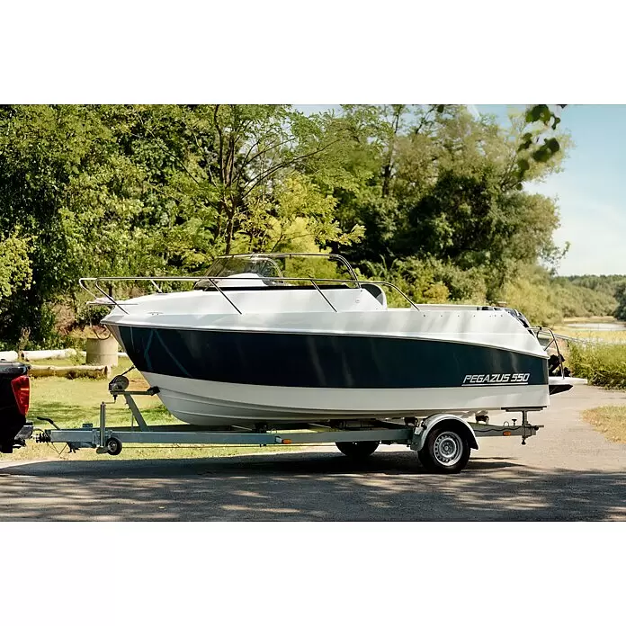 PEGAZUS GFK-Boot 550 Comfort - Umfangreiche Zusatzausstattung, Geeignet für: Max. 6 Personen, Nutzlast: 670 kg, CE-Klasse C - Weiß-dunkelblaues Pegazus 550 Boot auf verzinktem Trailer, an schwarzen LKW gekoppelt, im Freien an Bäumen und Wasser geparkt.