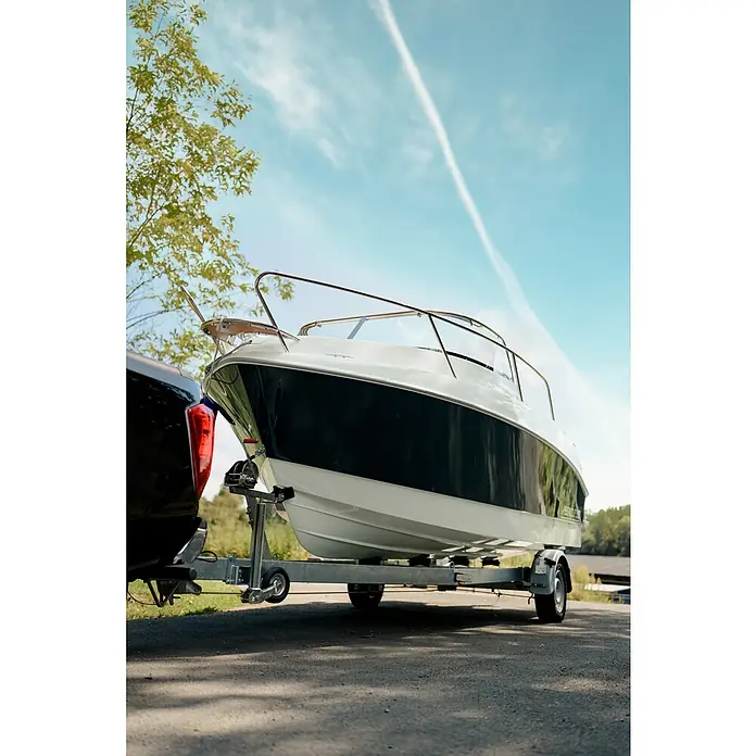 PEGAZUS GFK-Boot 550 Comfort - Umfangreiche Zusatzausstattung, Geeignet für: Max. 6 Personen, Nutzlast: 670 kg, CE-Klasse C - Ein elegantes, schwarzes und weißes Boot auf einem Anhänger, befestigt an einem Pick-up, bereit für neue Wasserabenteuer.