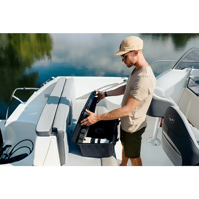 Wasserdichter Koffer EKO90 - L x B x H: 520 x 350 x 125 mm, Ohne Schaumstoffeinlage, Grau, Kunststoff - Mann öffnet einen schwarzen Schutzkoffer auf einem Boot, ideal für empfindliche Geräte wie Kameras oder Drohnen.