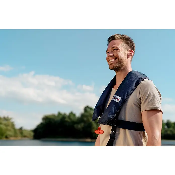 Marinepool Automatik-Rettungsweste ISO Classic 150N - Auftrieb: 150 N, Geeignet für Gewicht: 40 kg, Automatik/Manuell - Ein lächelnder Mann mit einer Marinepool-Schwimmweste an einem sonnigen Tag auf dem Wasser.