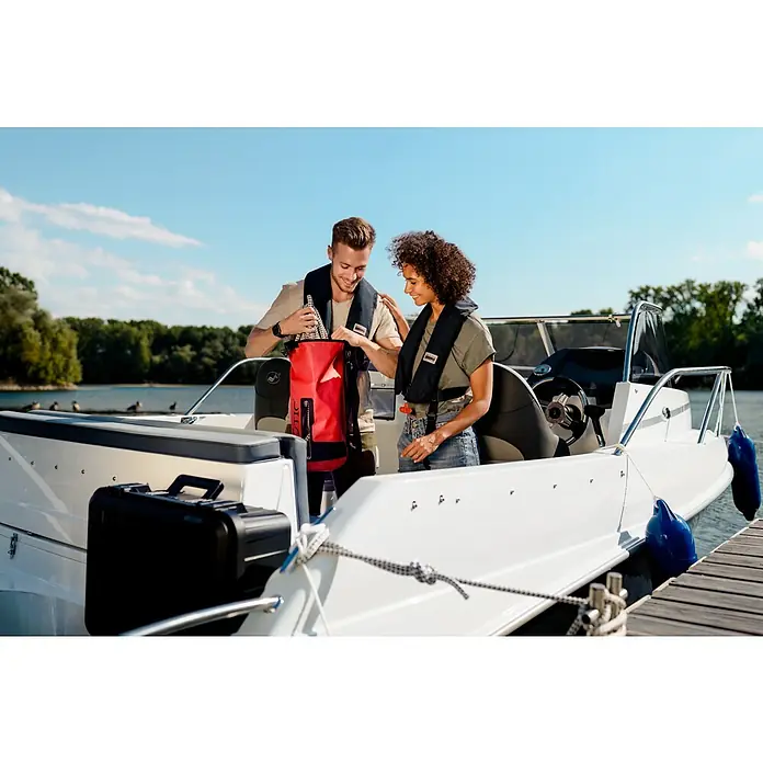 Wasserdichter Koffer EKO90 - L x B x H: 520 x 350 x 125 mm, Ohne Schaumstoffeinlage, Grau, Kunststoff - Zwei Personen auf einem Boot tragen Schwimmwesten. Eine rote wasserdichte Tasche steht im Vordergrund.