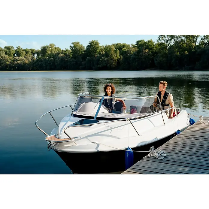 PEGAZUS GFK-Boot 550 Comfort - Umfangreiche Zusatzausstattung, Geeignet für: Max. 6 Personen, Nutzlast: 670 kg, CE-Klasse C - Ein weißes Motorboot mit zwei Personen liegt an einem hölzernen Steg vor einem ruhigen See. Das Boot ist modern und gepflegt.
