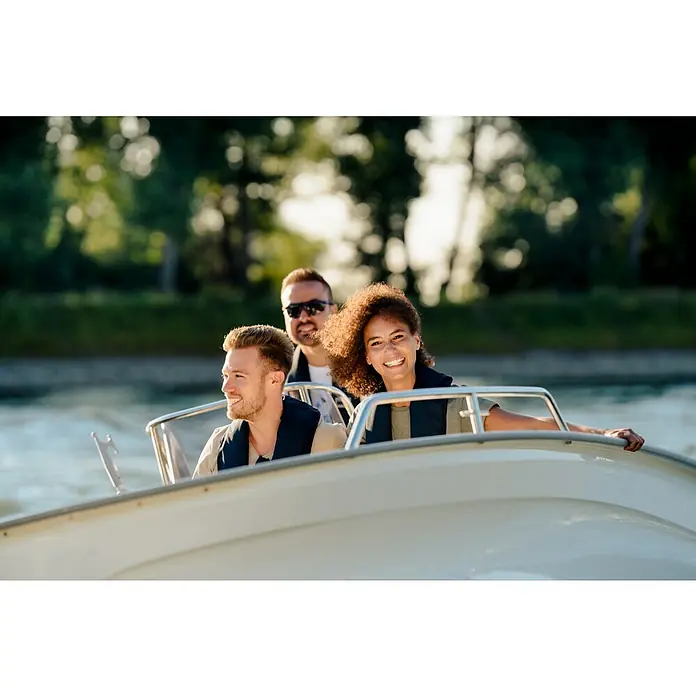 Marinepool Automatik-Rettungsweste ISO Classic 150N - Auftrieb: 150 N, Geeignet für Gewicht: 40 kg, Automatik/Manuell - Drei Personen genießen eine Bootsfahrt auf einem weißen Boot, alle tragen Schwimmwesten für die Sicherheit auf dem Wasser.
