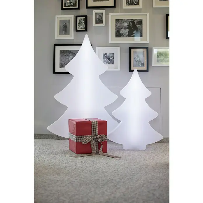 8 Seasons Design Shining LED-Weihnachtsleuchte Tree - 6 W, Weiß, L x B x H: 20 x 79 x 113 cm - Dekorative Weihnachtsszene mit einem roten Geschenk vor zwei leuchtenden, stilisierten Weihnachtsbäumen, ergänzt durch eine Bildergalerie an der Wand.