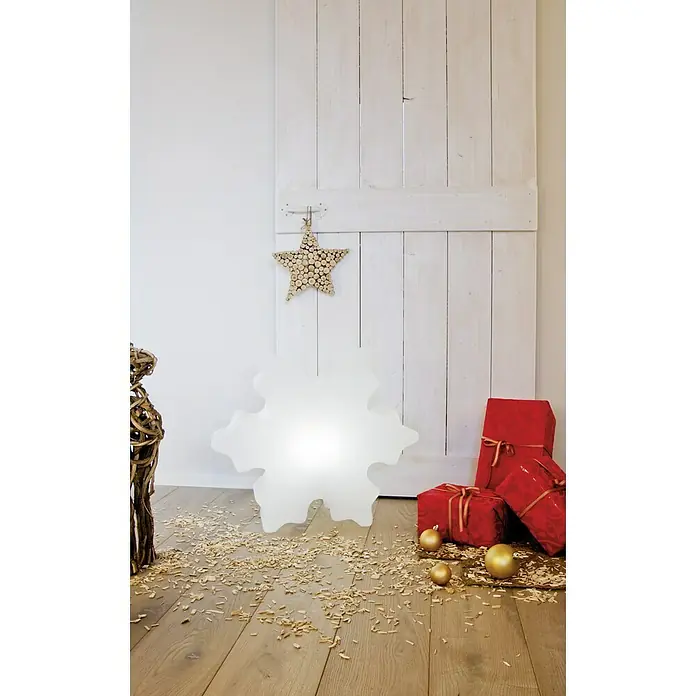 8 Seasons Design Shining LED-Solar-Weihnachtsleuchte Crystal - 2 W, Weiß, Durchmesser: 60 cm - Weihnachtliche Szene mit einem leuchtenden Schneeflocken-Dekoelement, roten Geschenken und einem Holzstern vor einer weißen Holzwand.