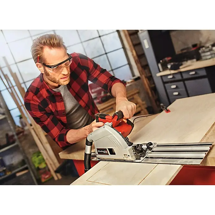 Einhell Expert Tauchsäge TE-PS 165 - 1.200 W, Leerlaufdrehzahl: 5.200 U/min - Mann mit Schutzbrille beim Zusägen von Holz mit einer Einhell Tauchsäge für präzise Schnitte in der Werkstatt.