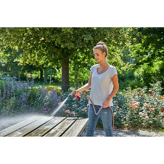 Gardena Reinigungsspritze Comfort ecoPulse - Kunststoff - Frau reinigt Gartentisch mit Gardena-Schlauch. Ideal für die Gartenarbeit, die Bewässerung und die Reinigung von Außenbereichen.