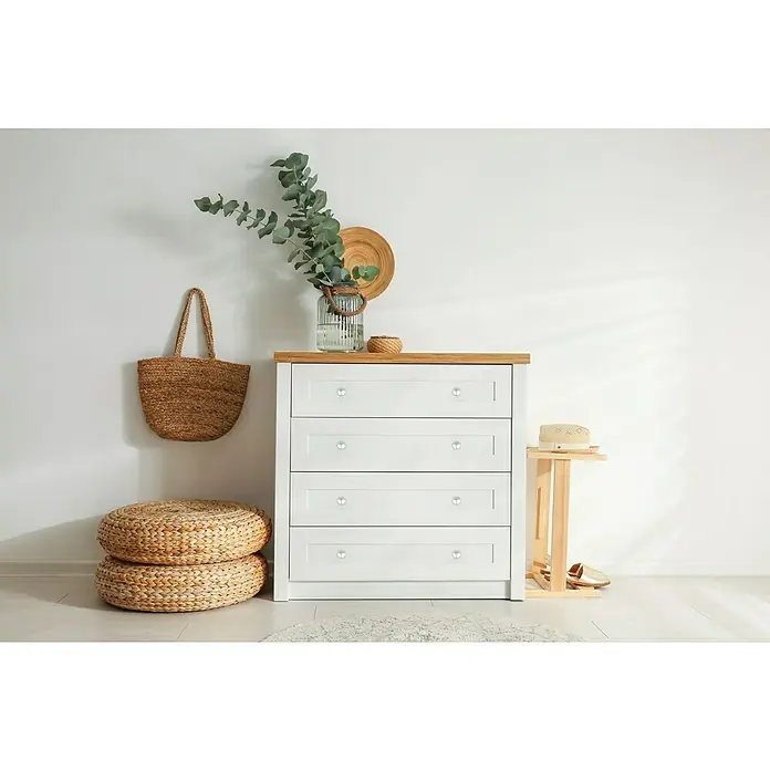 MöbelknopfTyp Möbelgriff: Knopf, Ø x H: 25 x 22 mm, Vernickelt - Eine weiße Kommode mit vier Schubladen und Holzplatte, dekoriert mit Pflanzen, einer Tasche und einem Hocker, die ein stilvolles Ambiente schaffen.