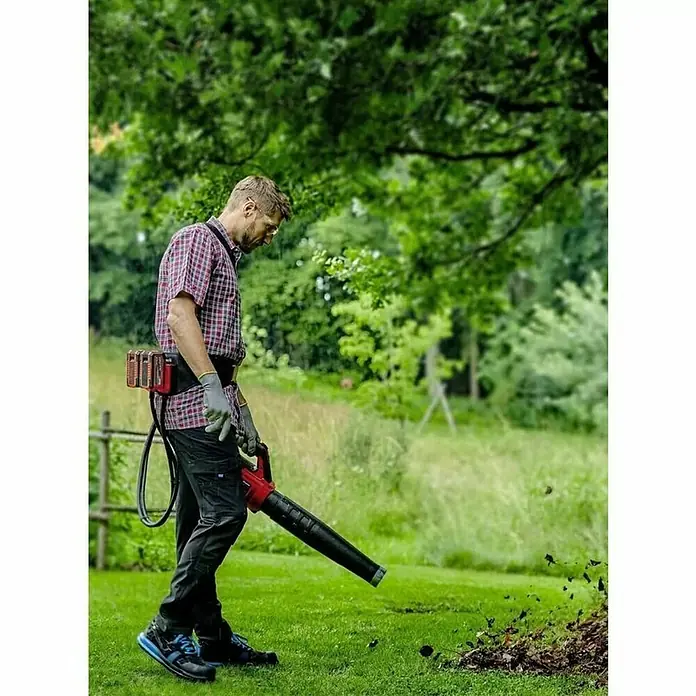 Einhell Cinturón GE-PB 36/18 Li - Largo: 150 cm, Específico para: Equipos de 18 V y 36 V Power X-Change - Un hombre usa un soplador de hojas inalámbrico en el jardín para quitar las hojas. Práctica herramienta de jardín para el orden en el exterior.