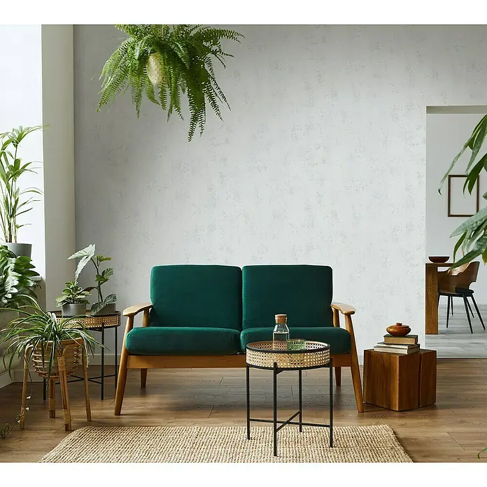 Marburg Vliestapete CELSIUS - Weiß/Aluminium, L x B: 10,05 x 0,53 m - Einladendes Wohnzimmer mit einem smaragdgrünen Sofa, ergänzt durch Beistelltische und Zimmerpflanzen, die eine ruhige, natürliche Atmosphäre schaffen.