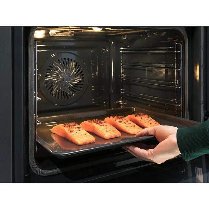 Electrolux Horno empotrado EOB8S39X - Número de tipos de calentamiento: 22 ud., Volumen horno: 70 l - Filetes de salmón se deslizan en un horno moderno sobre una bandeja para hornear, listos para cocinar.