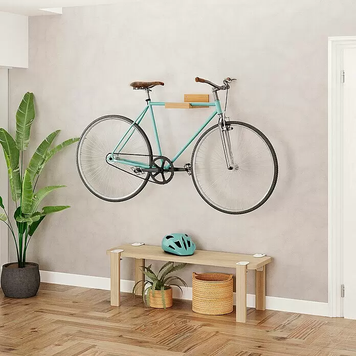 Rei Fahrradhalterung - L x B x H: 35 x 20 x 10 cm, Belastbarkeit: 25 kg - Hellblaues Fahrrad an einer hölzernen Wandhalterung über einer hellen Holzbank mit Helm.