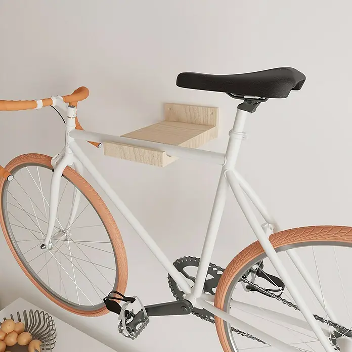 Rei Fahrradhalterung - L x B x H: 35 x 20 x 10 cm, Belastbarkeit: 25 kg - Ein weißes Fahrrad hängt an einer hölzernen Wandhalterung mit orangefarbenen Akzenten. Das Fahrrad ist an der Wand befestigt und spart Platz.