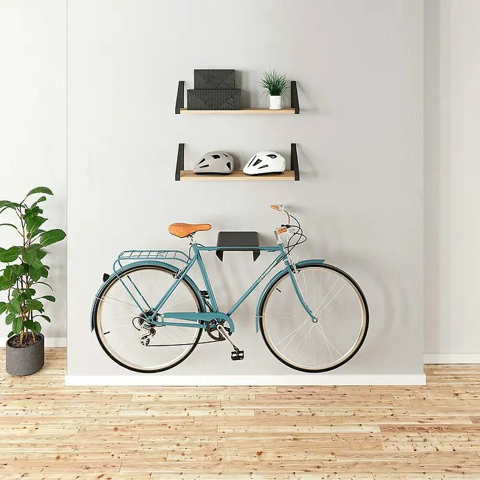 Rei Fahrradhalterung - L x B x H: 365 x 280 x 85 mm - Das Bild zeigt ein blaues Fahrrad, das an einer Wandhalterung hängt, darüber Regale mit Deko und Helmen in einem stilvollen Raum.