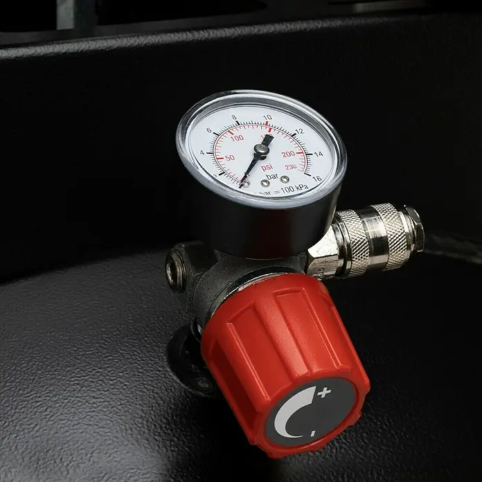 Herkules Compresor Pro-Line B3800 B/200 vertical - Presión máx.: 10 bar, 3.000 W - Primer plano de un manómetro con un botón de ajuste rojo, que muestra la presión tanto en psi como en bar, montado en un dispositivo negro.