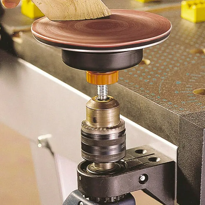 Wolfcraft Soporte para taladro - L x An: 43 x 43 mm, Plástico - Primer plano de un disco de lijado con papel de lija en un banco de trabajo. La herramienta está diseñada para lijar superficies de madera.