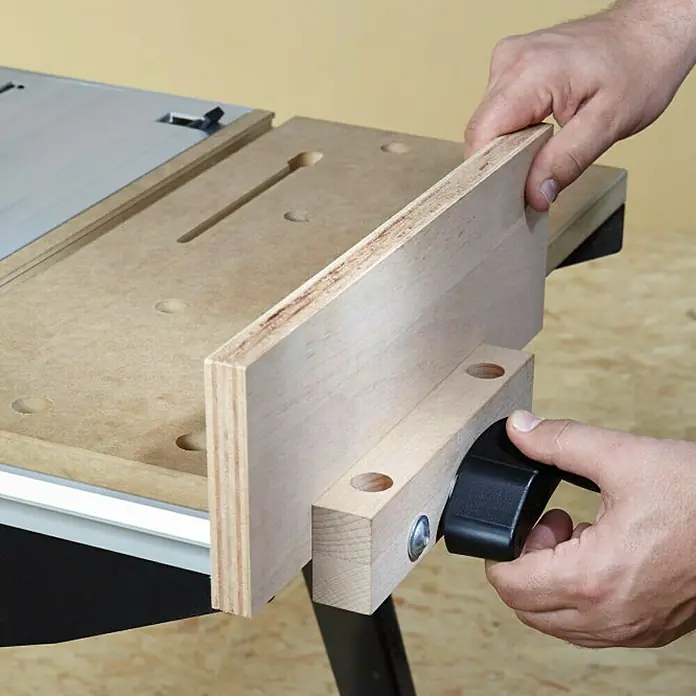 Wolfcraft Master Cut Banco de trabajo 1500 - Altura de trabajo: 865 mm, Carga soportada: 200 kg, Negro - Un primer plano de un banco de trabajo con una guía de madera montada que está siendo ajustada por una persona.