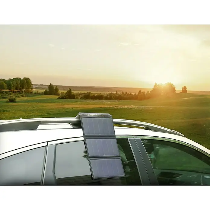 Yard Force Solar-Powerbank LX PB21 - 48,1 Wh, 65 x 28,5 x 1,5 cm - Solarpanel auf Autodach vor grüner Landschaft bei Sonnenuntergang. Ideal für umweltfreundliche Energieversorgung unterwegs.