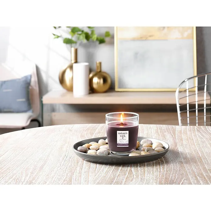 Woodwick Nature's Wick Duftkerze - Im Glas, Wildberry Jasmine, Anzahl Dochte: 1 Stk. - Nahaufnahme einer "Nature's Wick" Kerze mit Wildbeeren- und Jasmin-Duft, umgeben von Steinen auf einem Tisch.