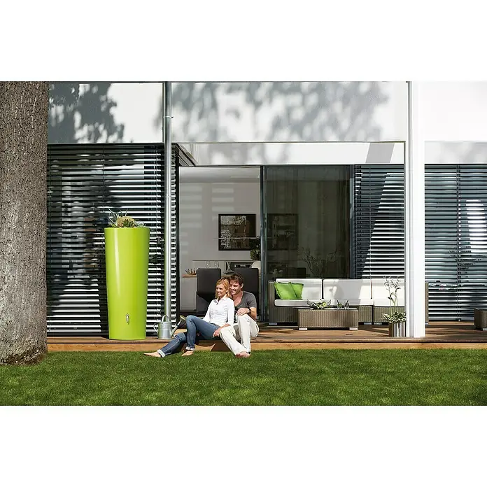 Garantia Modern Line Regenspeicher Color 2 in 1 - 350 l, Apple - Zeitgenössisches Haus mit einer grünen Regentonnen neben einem Paar, das die Natur genießt, die Funktionalität und Ästhetik vereint.
