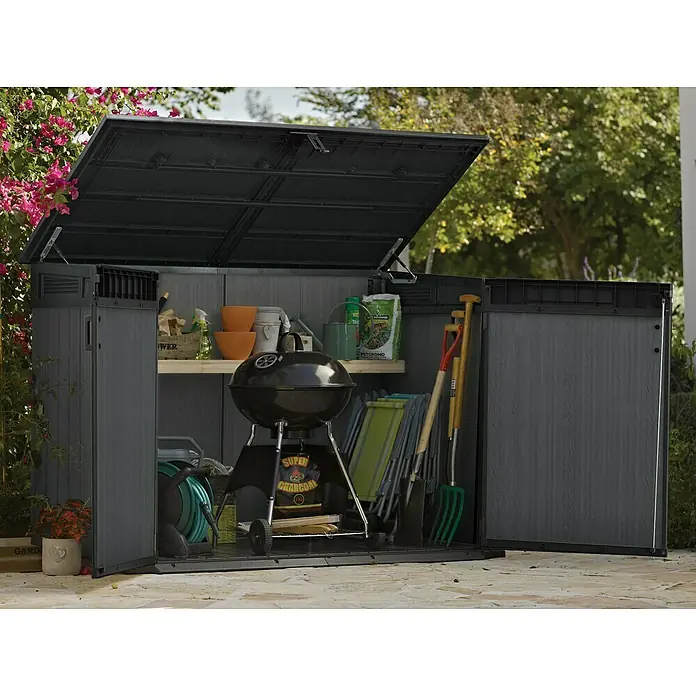 Keter Truhe Cortina Mega - Außenmaß inkl. Dachüberstand (B x T): 191 x 109 cm, Kunststoff, Anthrazit/Schwarz - Offener Gartenschrank mit Grill, Gartengeräten und Zubehör auf einer Terrasse, umgeben von Grün. Praktische Gartenaufbewahrung.