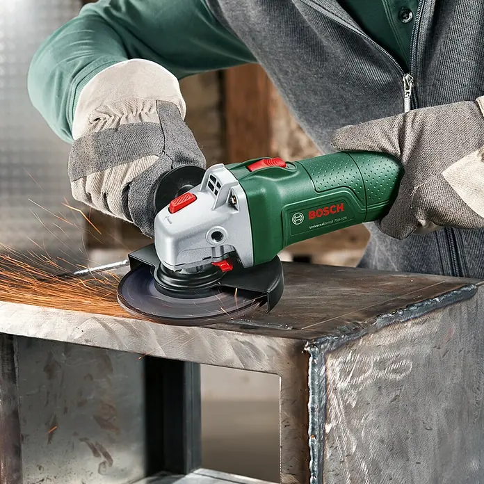 Bosch Elektro-Winkelschleifer UniversalGrind 750-125 - 750 W, Durchmesser Scheibe: 125 mm, Leerlaufdrehzahl: 12.000 U/min - Ein Bosch Winkelschleifer UniversalGrind 750-125 wird zum Schleifen von Metall verwendet, wobei Funken fliegen.