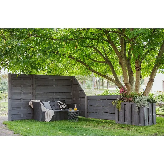 Sichtschutzelement Nevada - 89 x 179 cm, Grau - Entspannende Gartenszene mit grauer Holzgartenlounge, Kissen und einem Beistelltisch unter einem grünen Baum, der Schatten spendet.