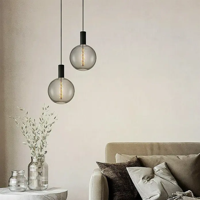 Home Sweet Home LED-Lampe Vintage Globe-Form E27 - E27, Dimmbar, Warmweiß, 20 lm, 6 W, Farbe: Smoky - Zwei moderne Pendelleuchten mit runden, rauchfarbenen Glaslampenschirmen und schwarzem Zubehör hängen über einem stilvollen Wohnzimmerbereich.