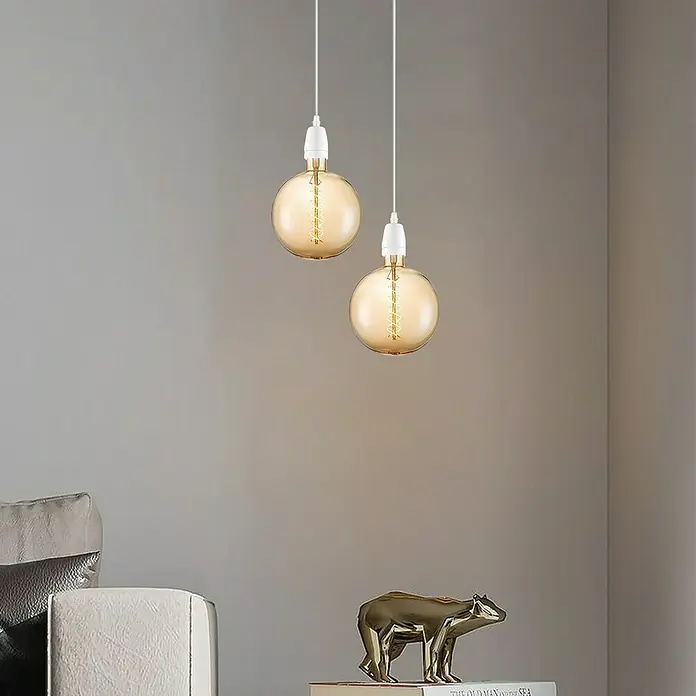 Home Sweet Home LED-Lampe Vintage Globe-Form E27 - E27, Dimmbar, Warmweiß, 220 lm, 6 W, Farbe: Gold - Zwei goldene Pendelleuchten mit weißen Kabeln und Fassungen vor einer grauen Wand.